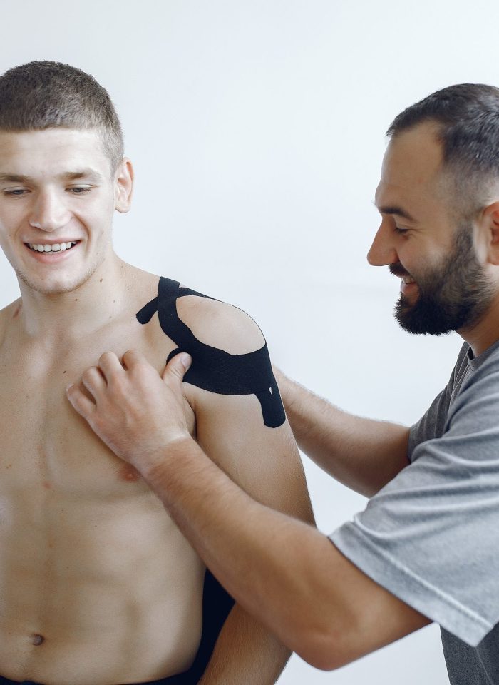 Doctor glues a tepee to an athlete at the hospital Kinesiology doctor. Sportsmen at the hospital. Man use the teppe